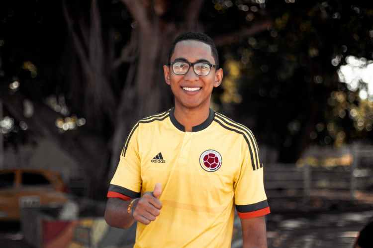 photo of smiling man in yellow and black adidas jersey shirt with his thumb up